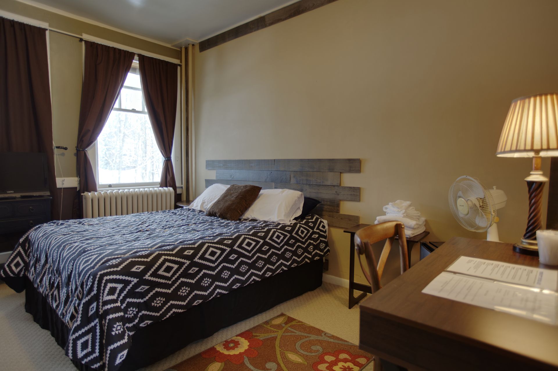 A bedroom with a bed , desk , lamp and window