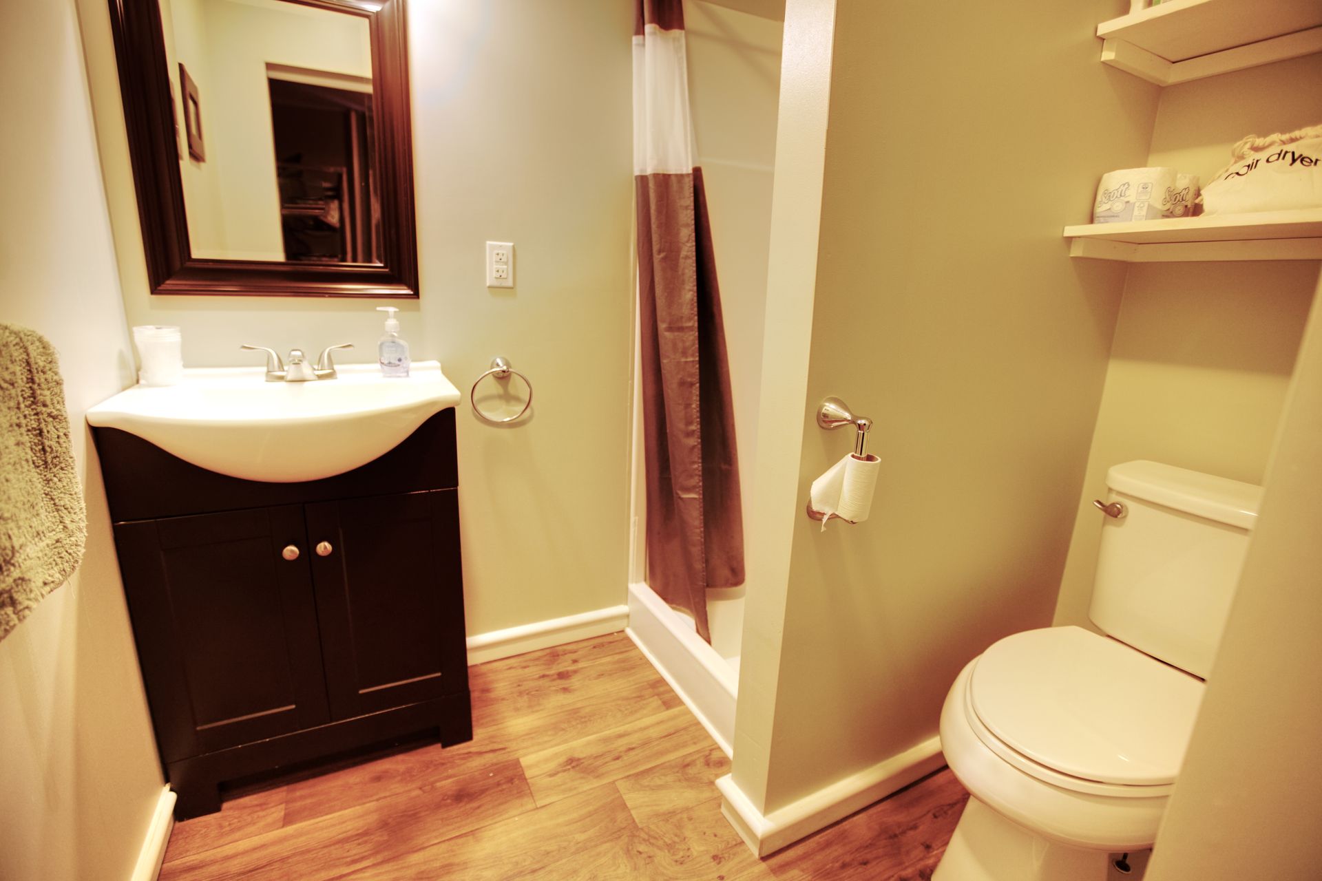 A bathroom with a toilet , sink , mirror and shower.