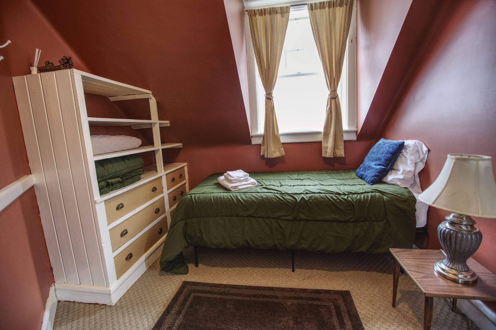 A bedroom with a single bed and a lamp