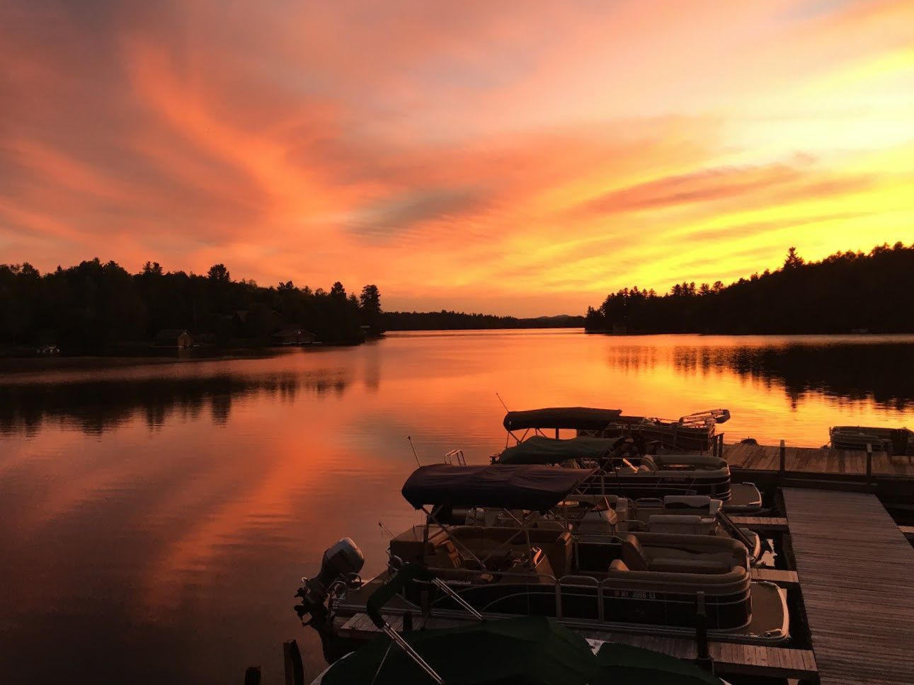 A sunset over a lake with boats docked at the dock