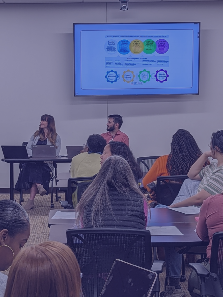 A group in a conference room looks to a screen