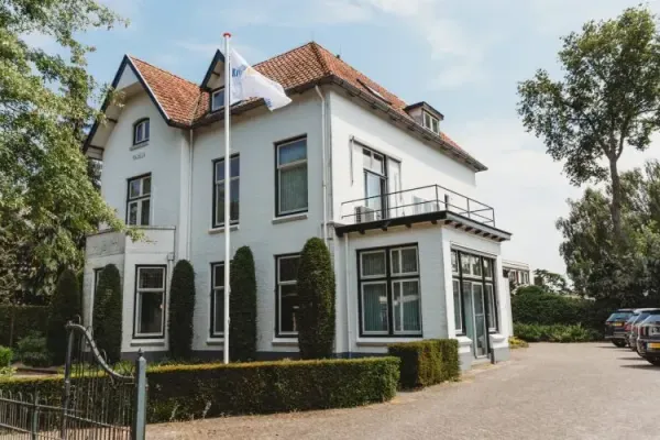 Een groot wit huis met een vlag ervoor