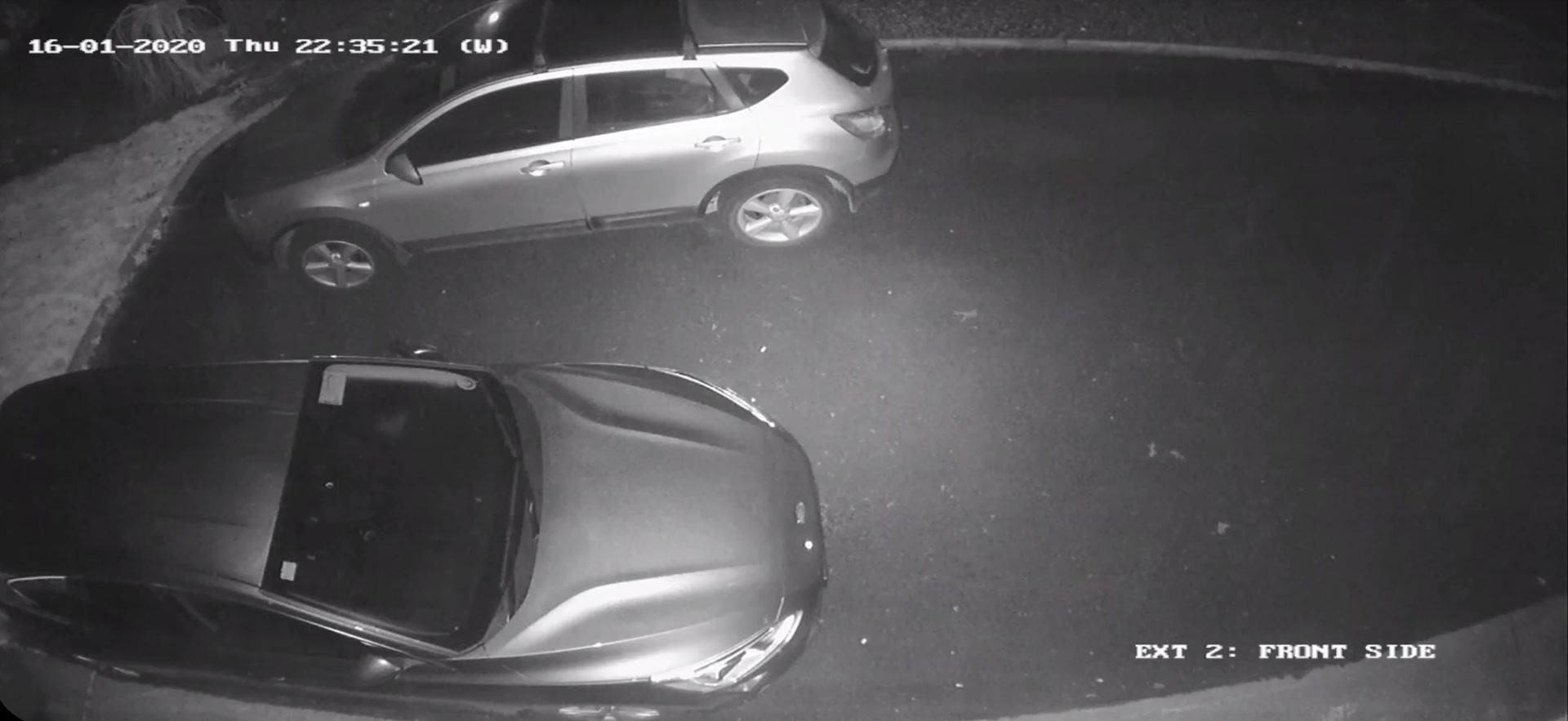 Two cars are parked in a dark parking lot.