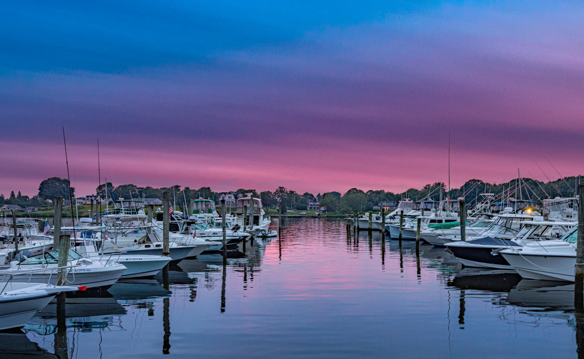 A bunch of boats are docked in a harbor at sunset.