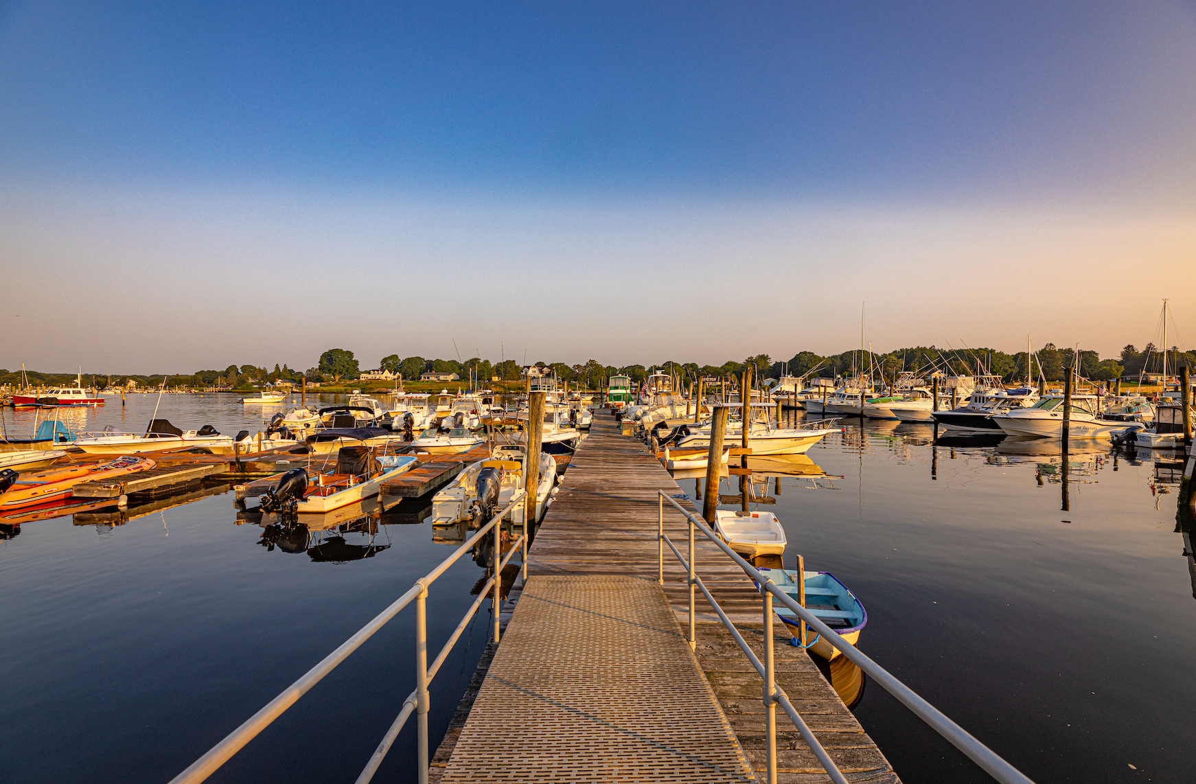 A dock with boats docked at a marina at sunset.
