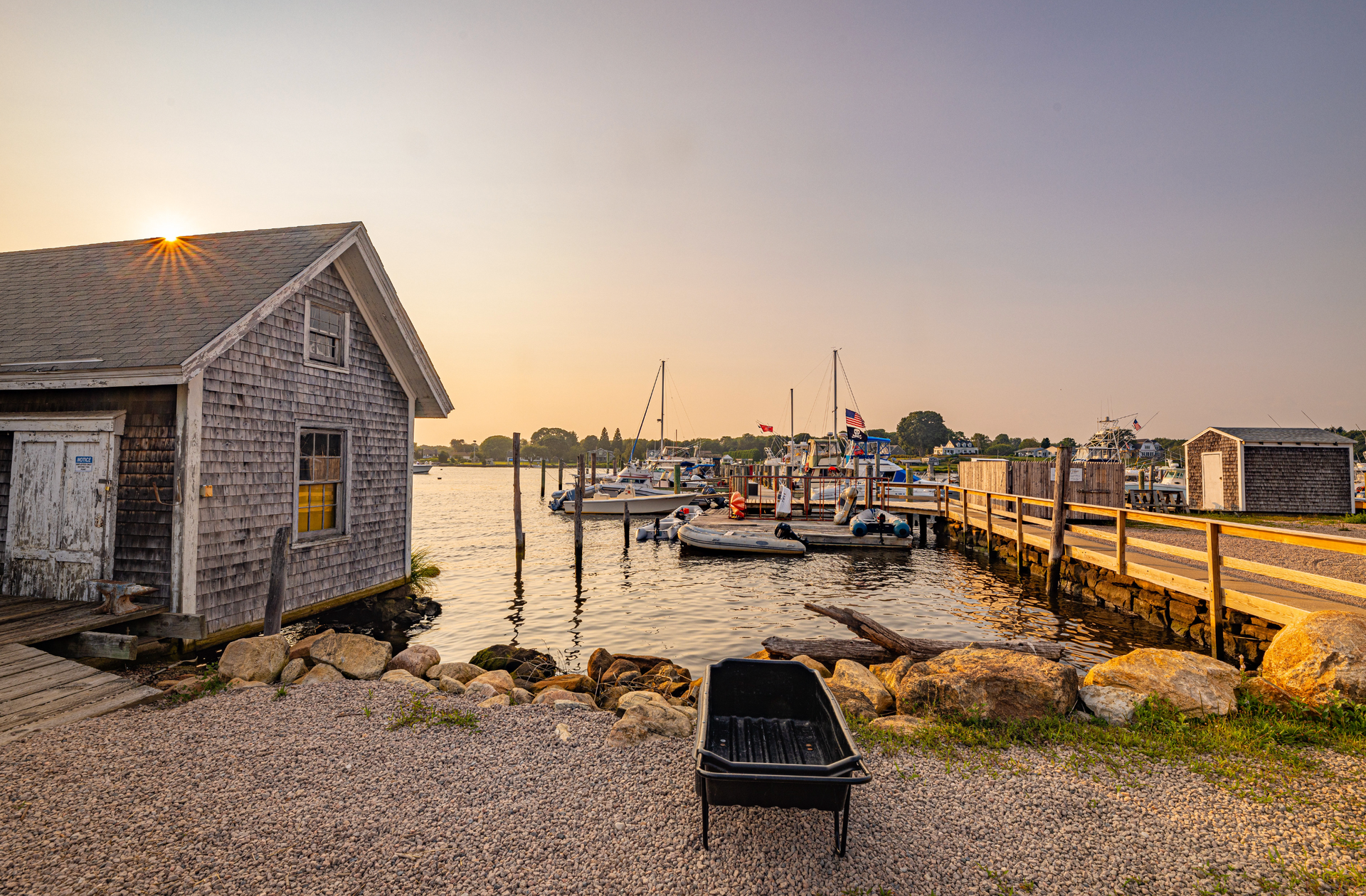A dock with boats docked in it and a shed in the background.