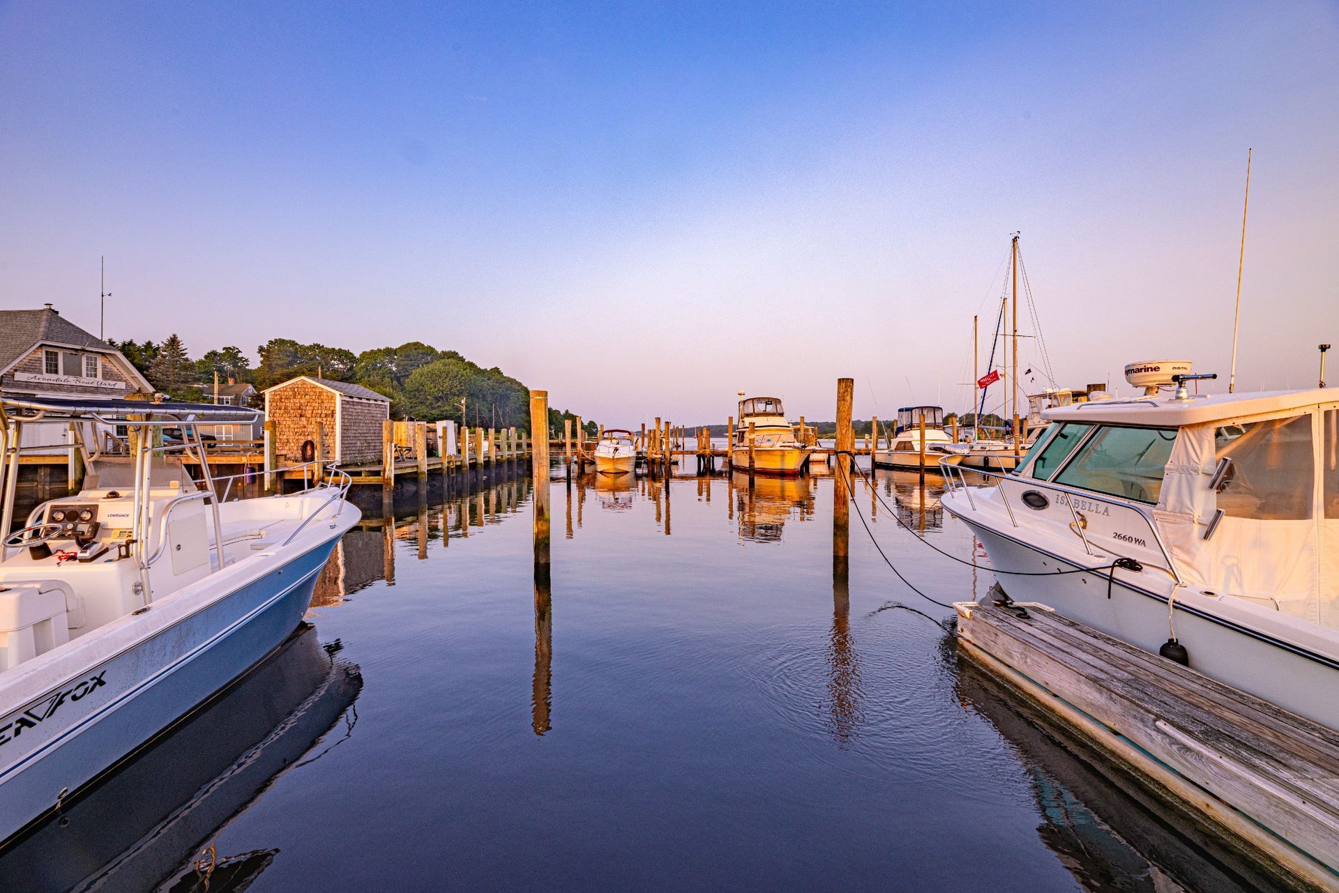 A row of boats are docked in a marina.
