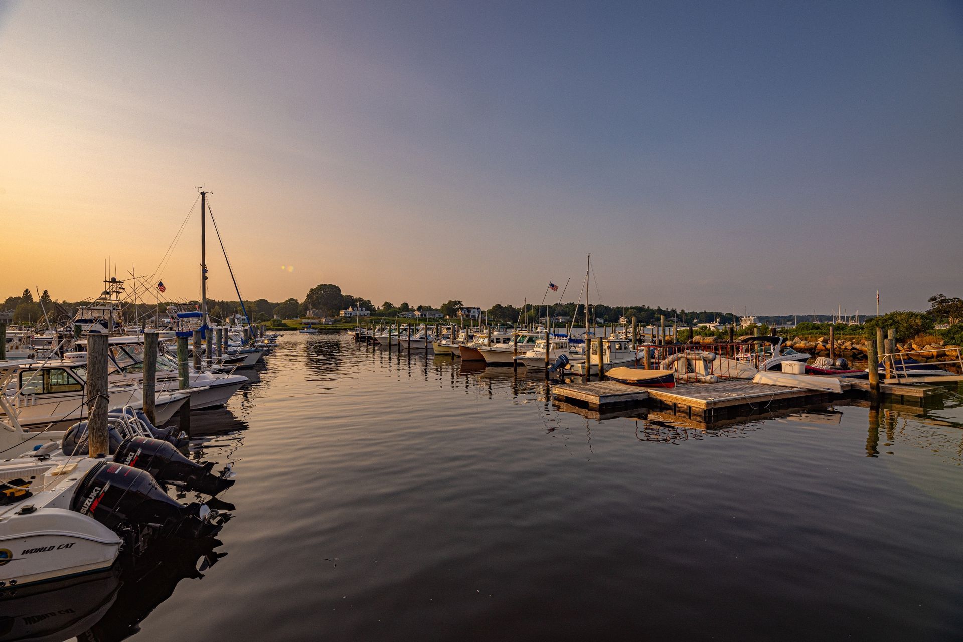 A marina filled with lots of boats docked at sunset.