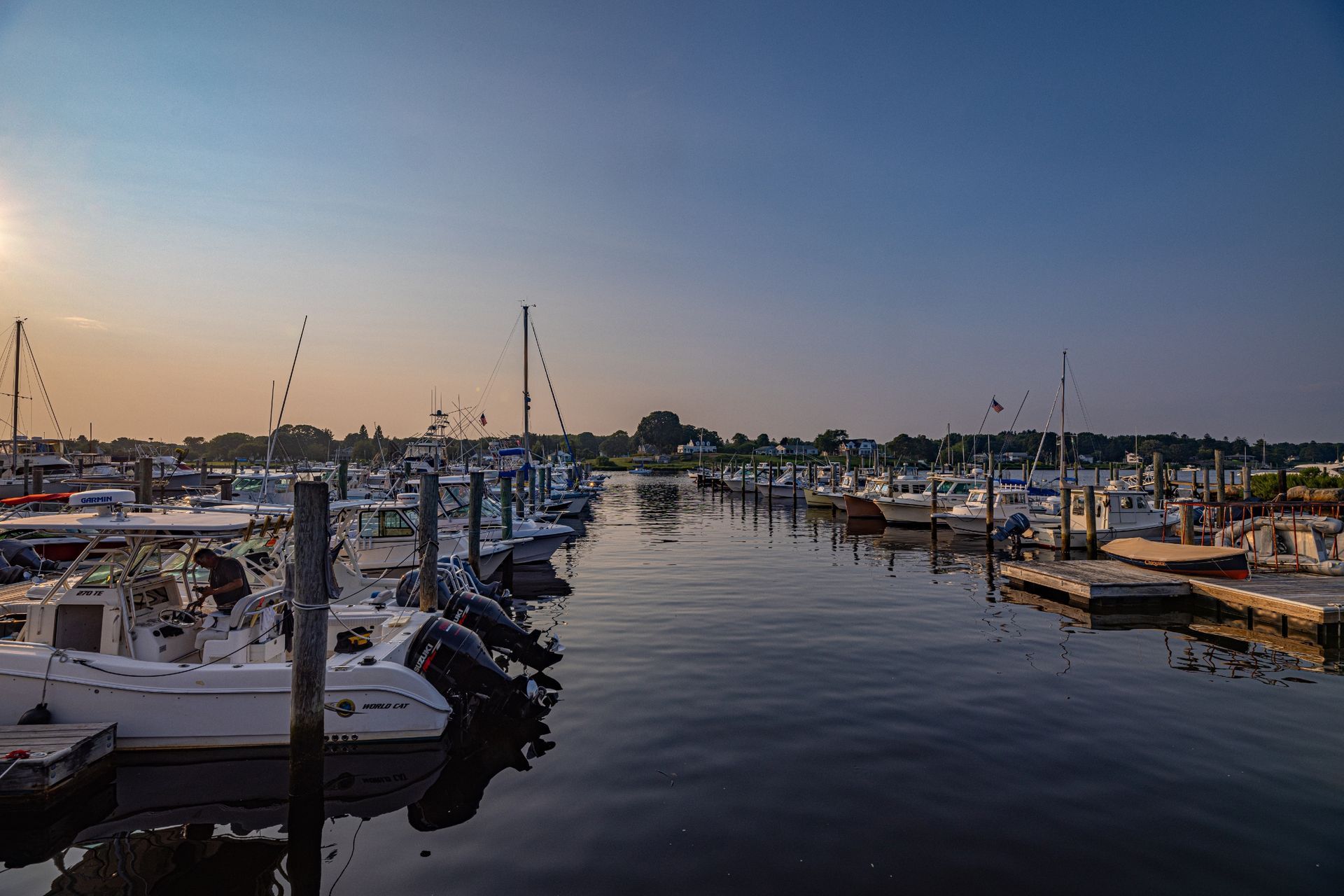 A marina filled with lots of boats docked at sunset.