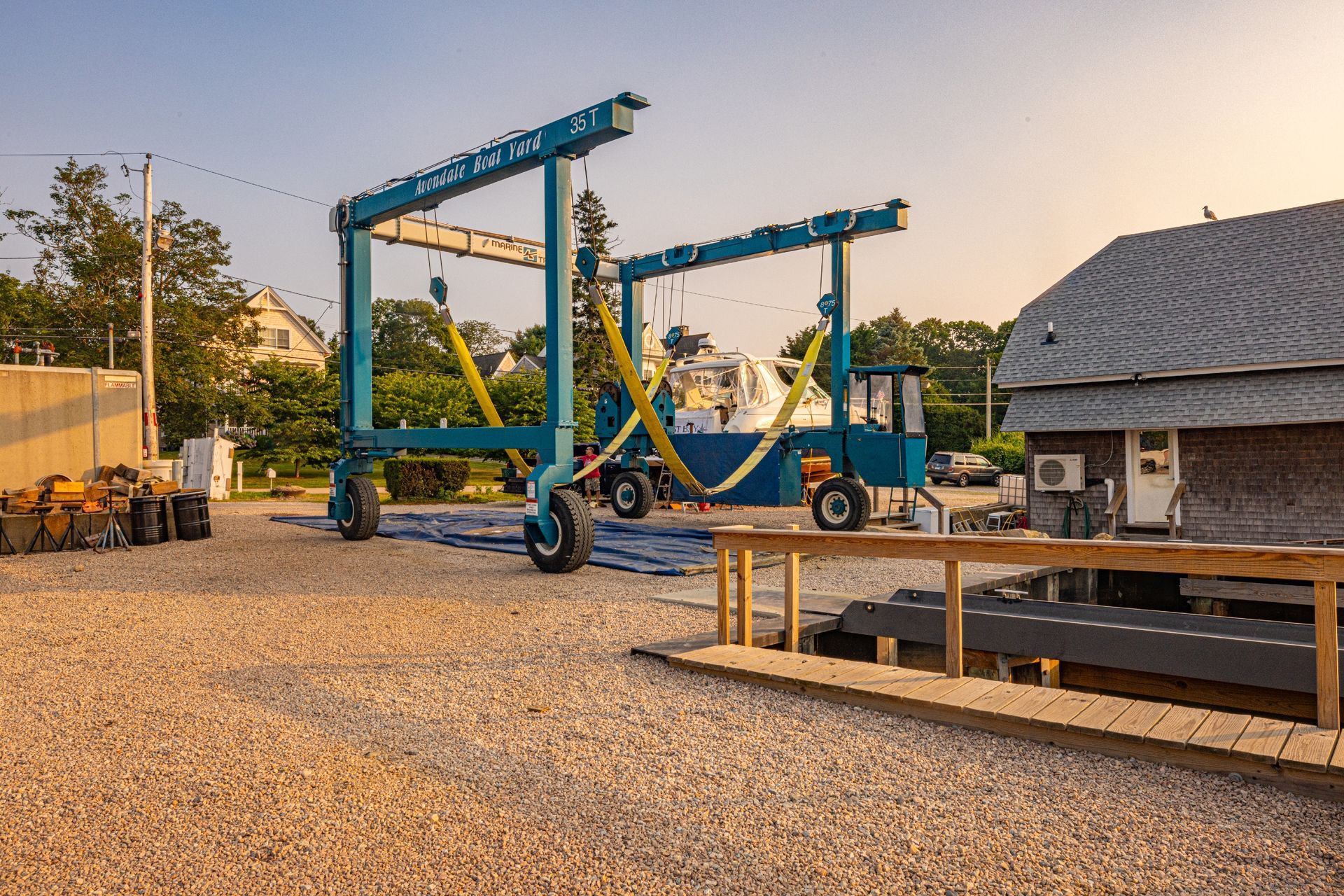 A large crane is sitting in a gravel lot next to a building.