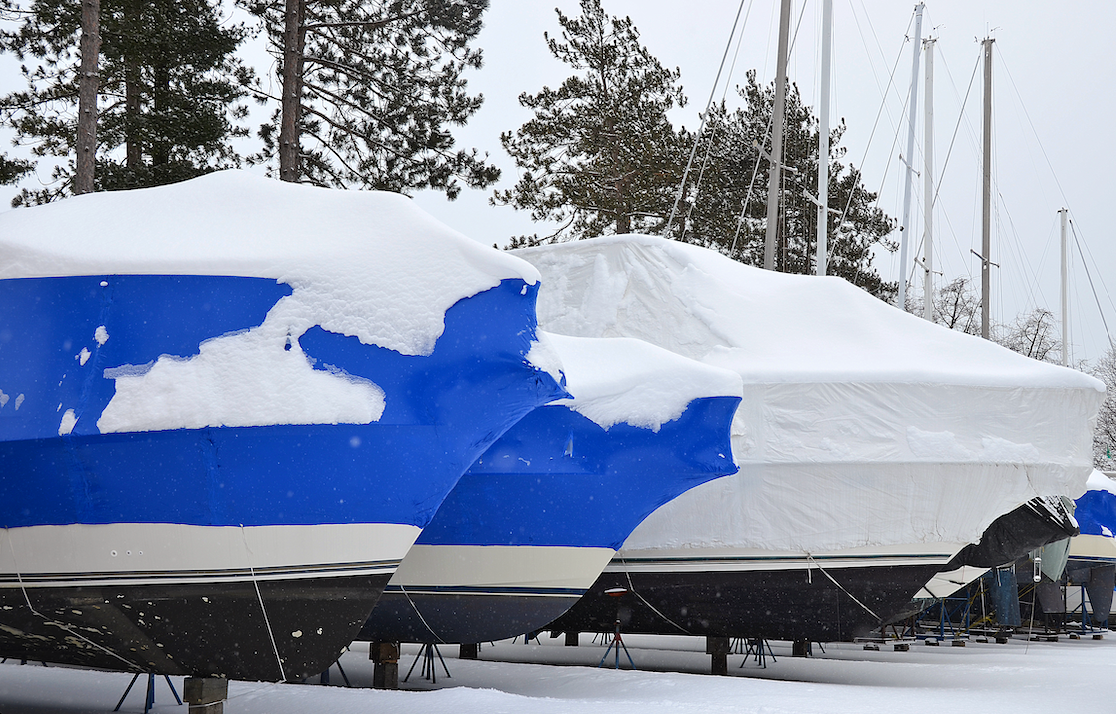 A blue and white boat is covered in snow.