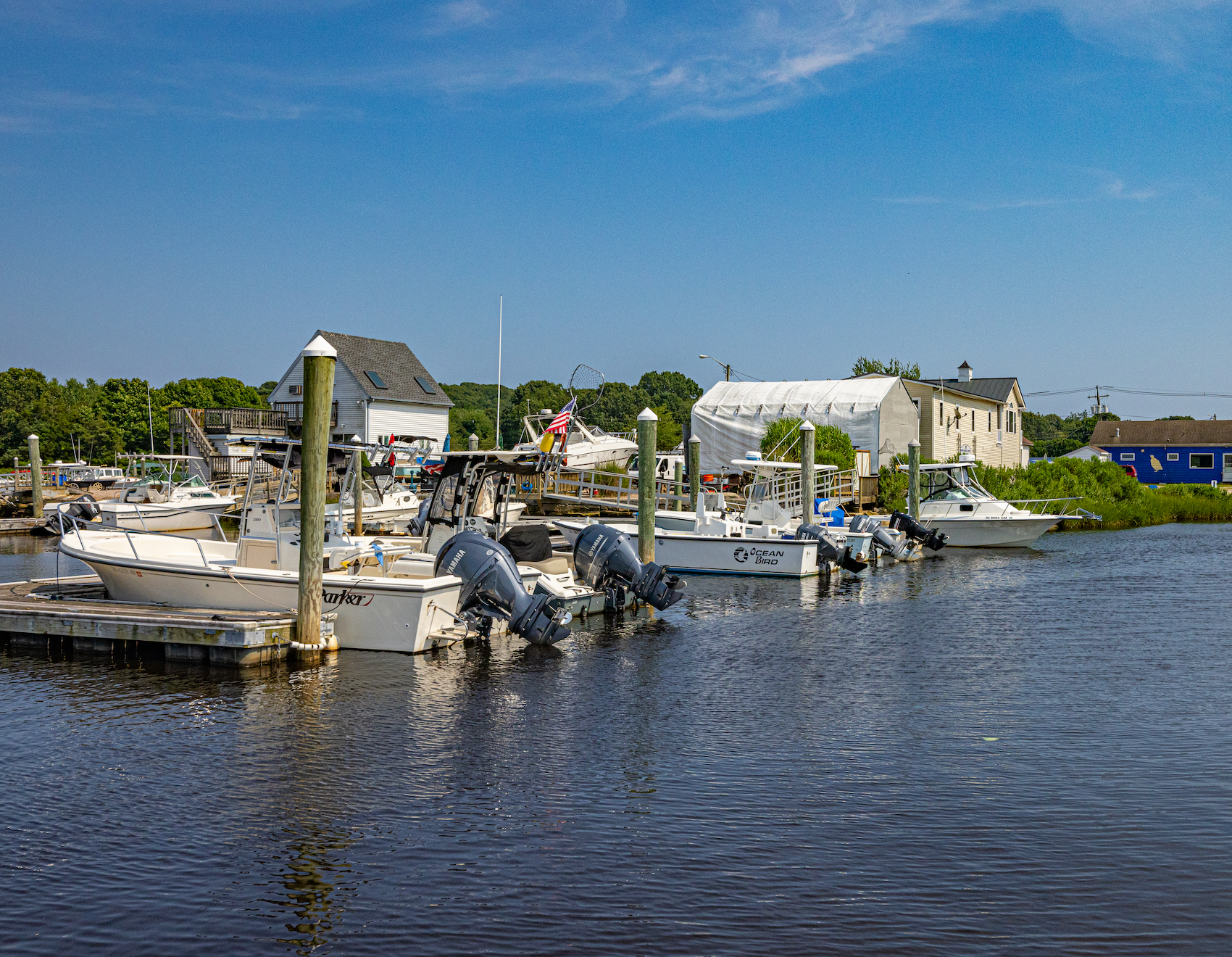 A row of boats are docked at a marina on a sunny day.