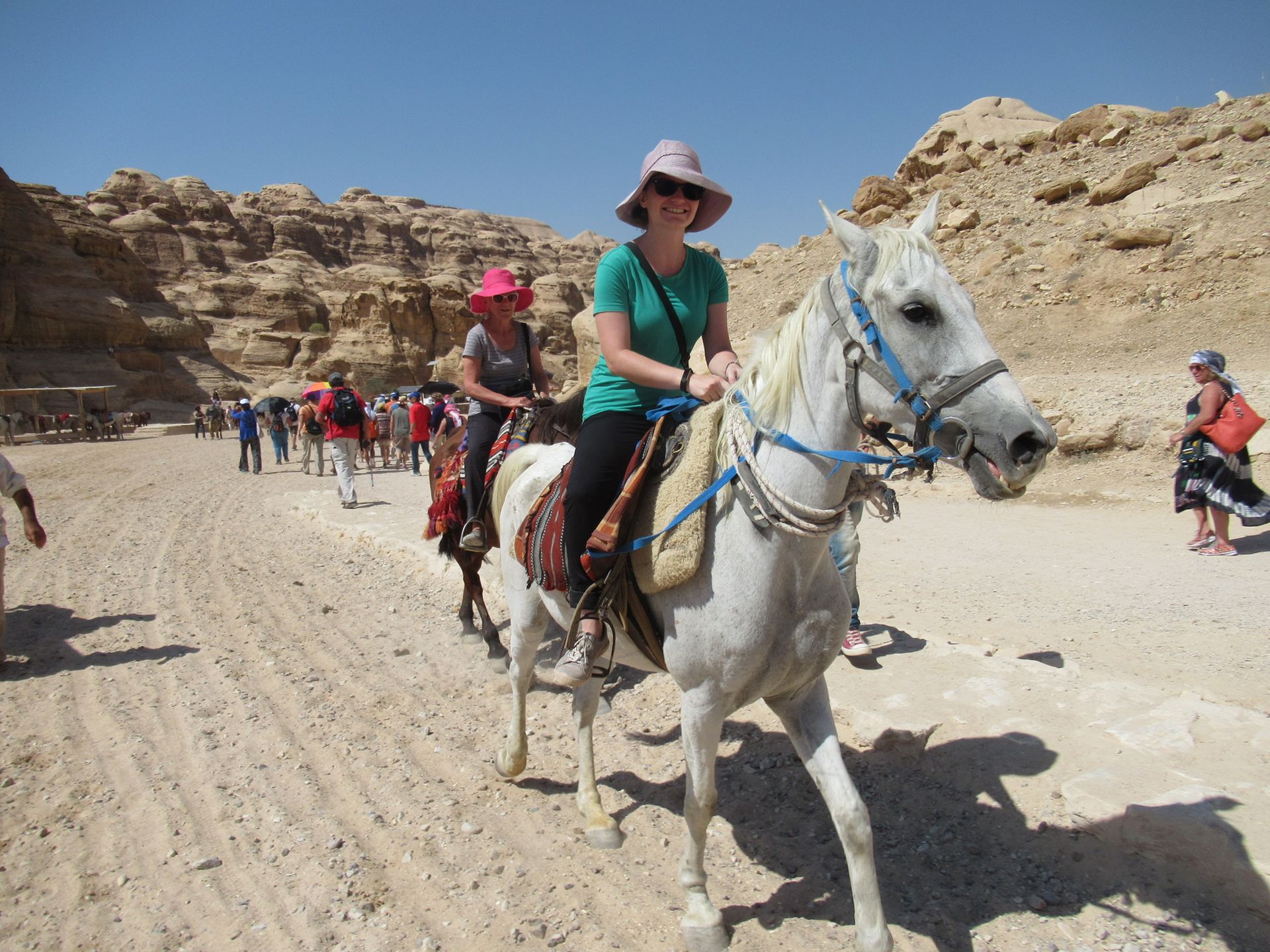 A woman is riding a white horse in the desert