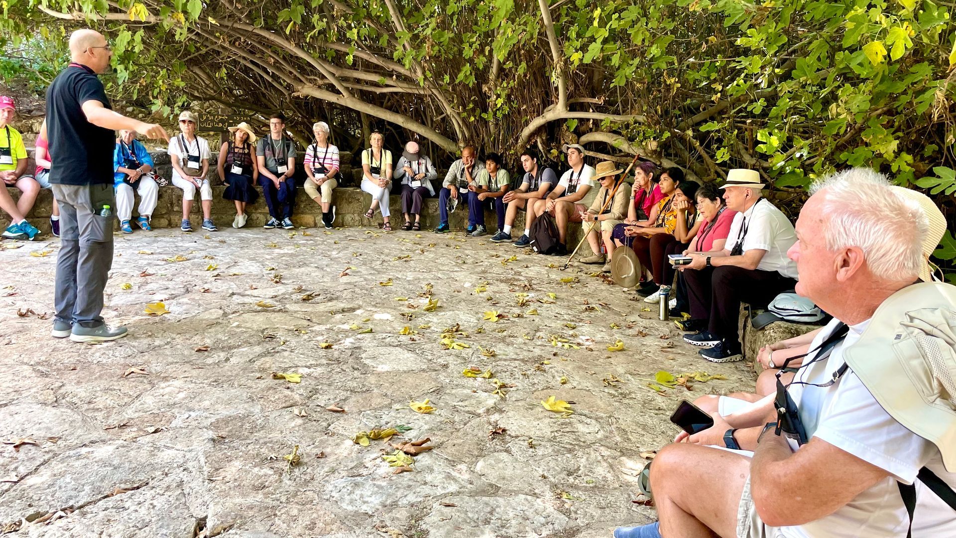 A man is standing in front of a group of people sitting in a circle.