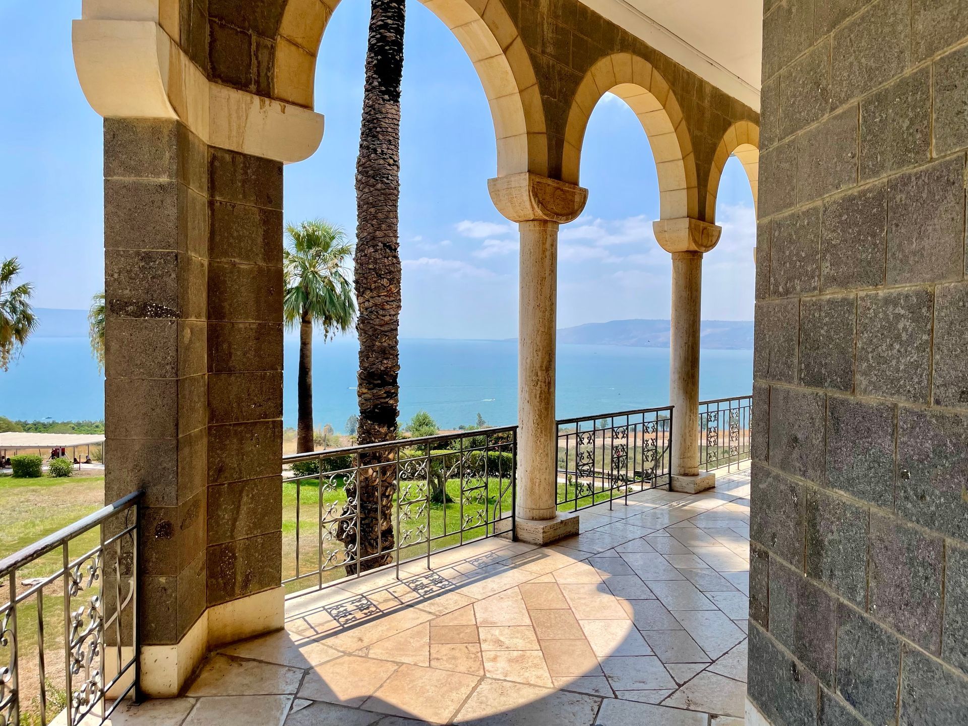 A balcony with a view of the ocean and palm trees.