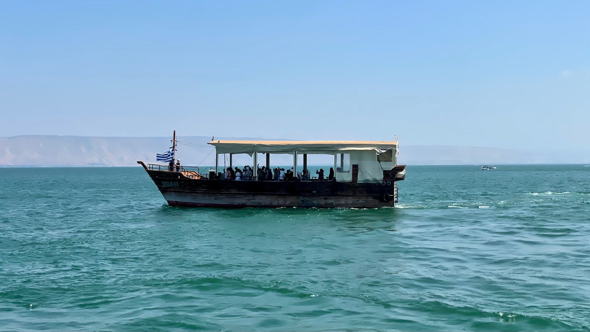 A boat with people on it is floating on top of a body of water.