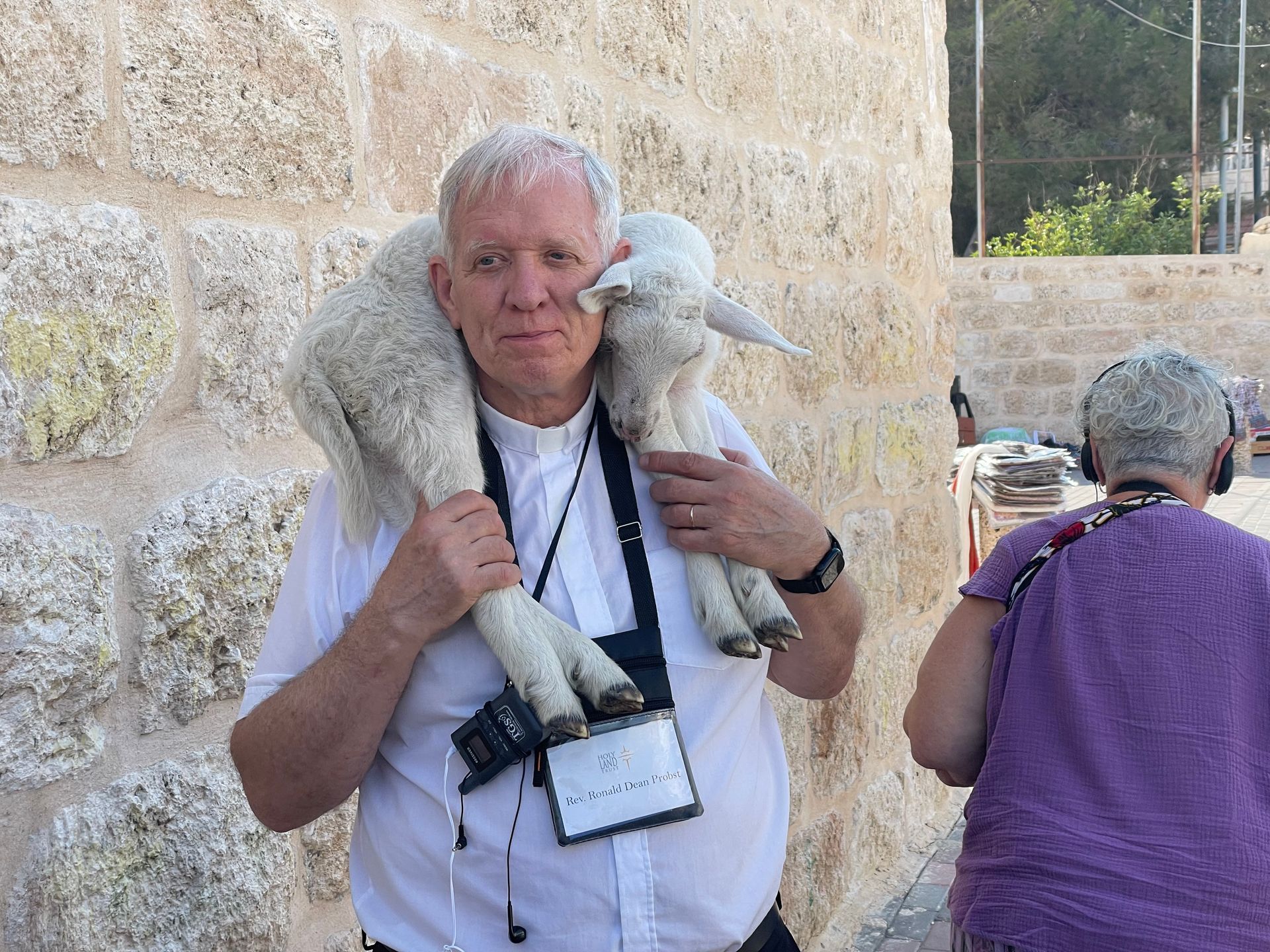 A priest is carrying a sheep on his shoulders.