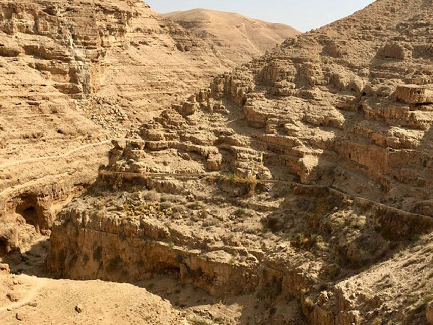 A canyon in the desert with mountains in the background