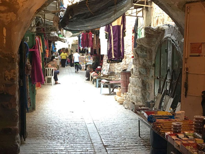 A narrow alleyway filled with lots of shops and people.