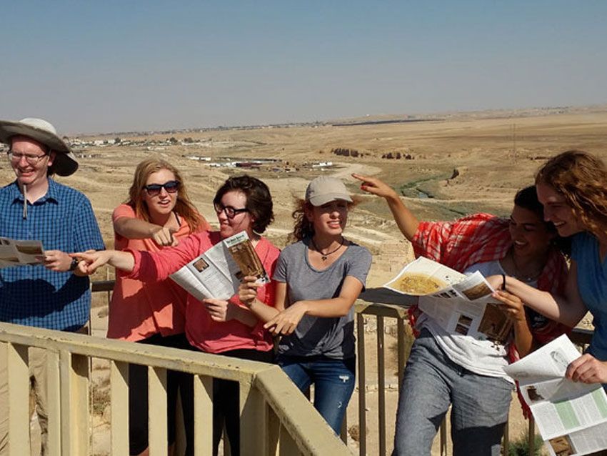 A group of people are standing on a balcony looking at a map.
