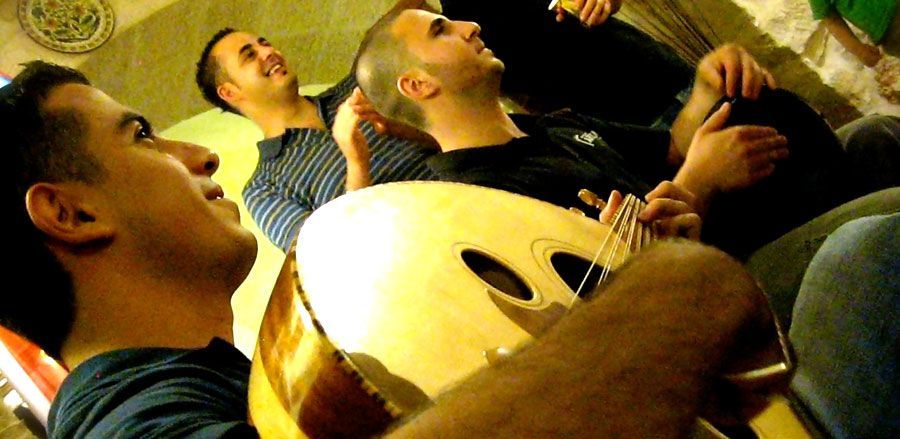 A group of men are sitting on a couch playing guitars