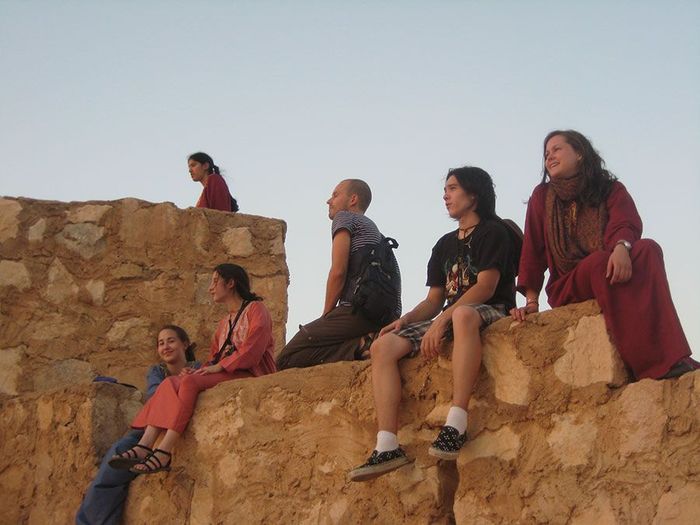 A group of people sitting on top of a stone wall