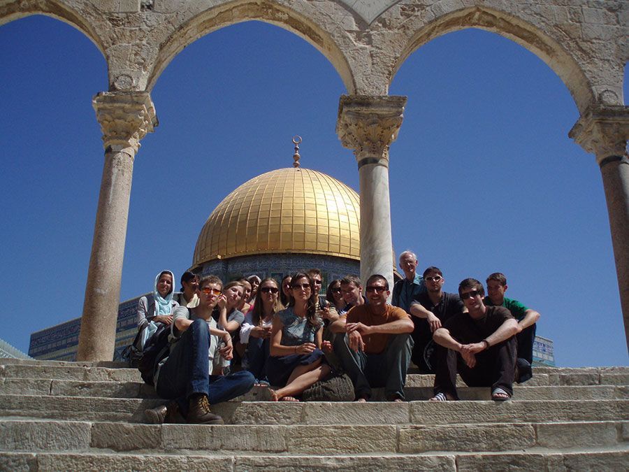 A group of people are posing for a picture in front of a dome