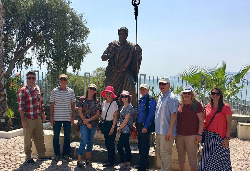 A group of people are posing for a picture in front of a statue.