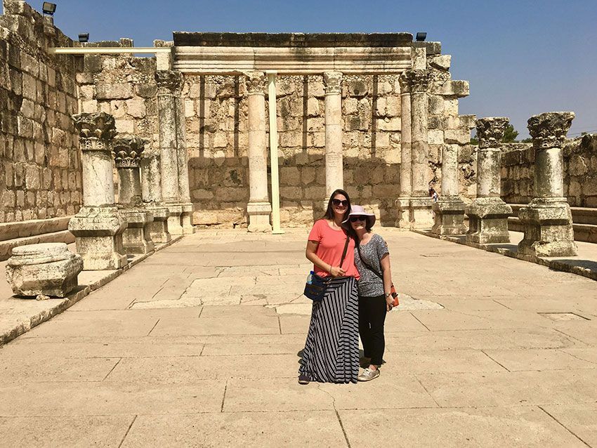 Two women are posing for a picture in front of an ancient building.