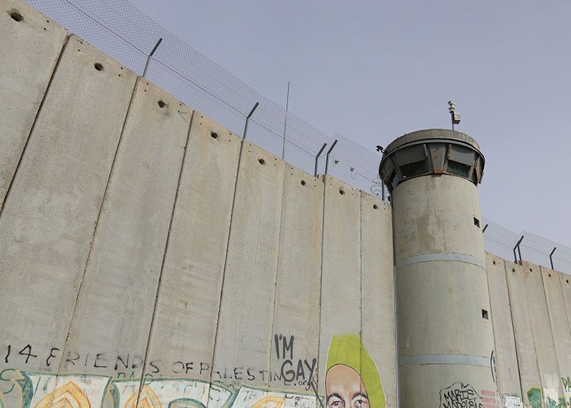 The separation wall with graffiti on it that says 