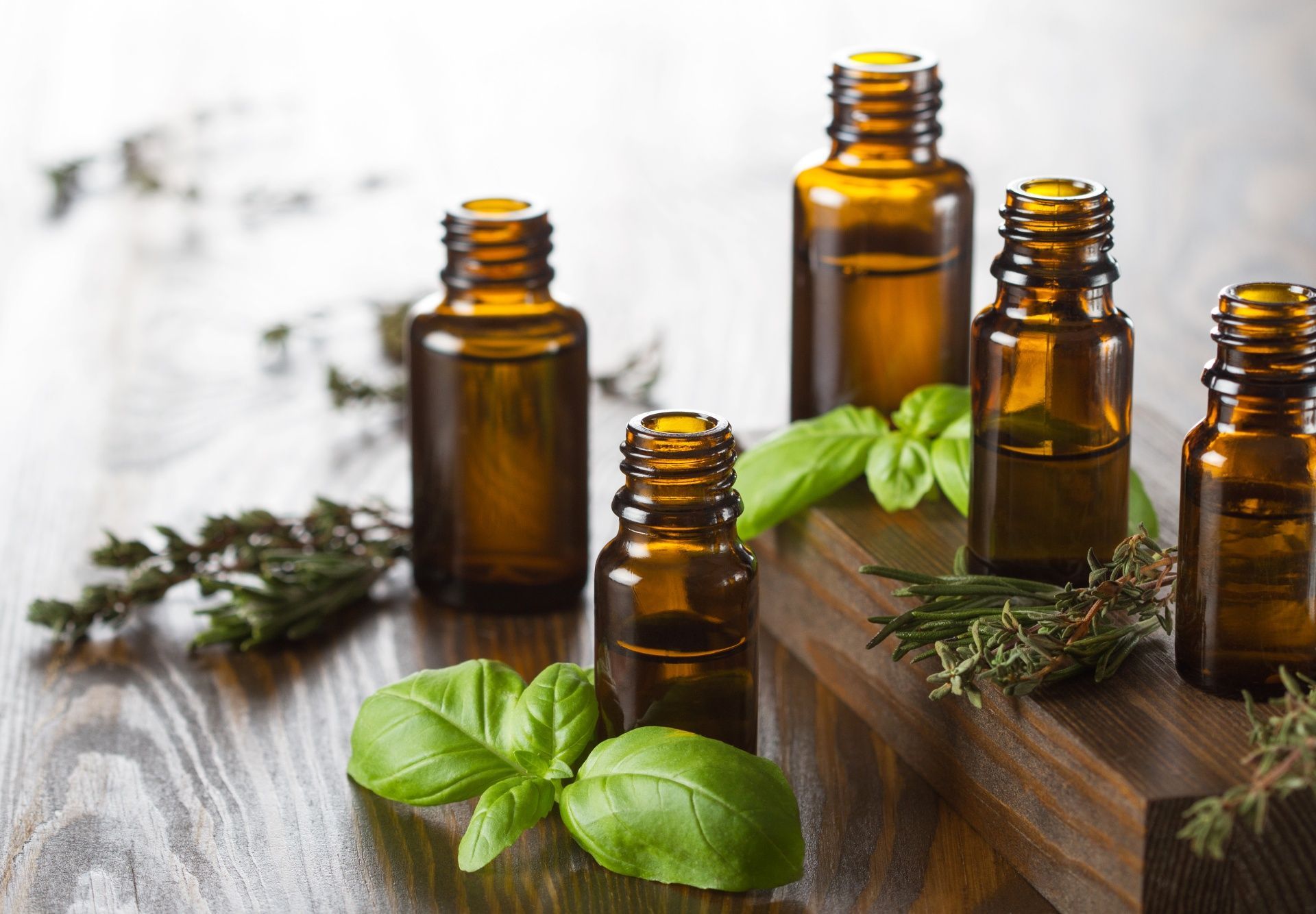 A wooden table topped with bottles of essential oils and herbs.