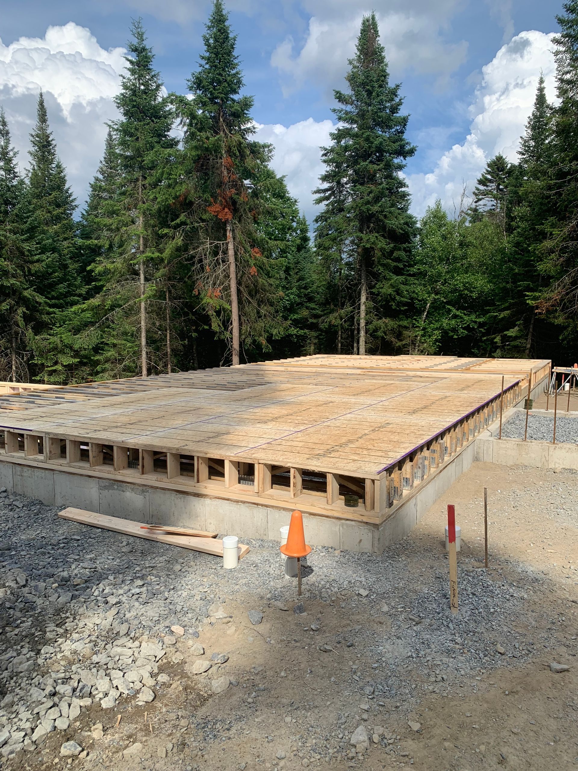 Fondations d'un bâtiment en construction, avec un plancher en bois posé sur du béton.