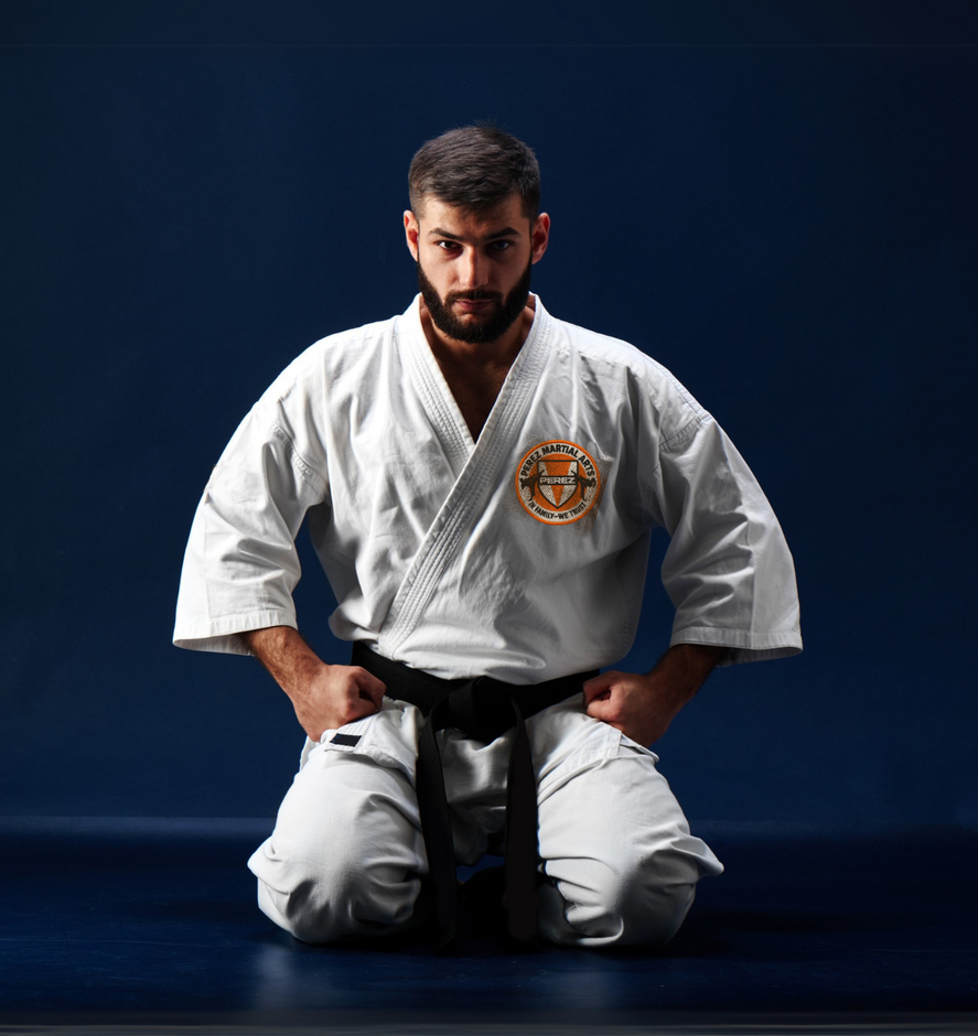 A man in a white karate uniform is kneeling down