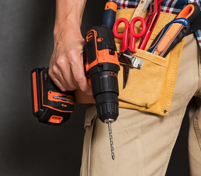 A handyman holds a power drill for repair and installation