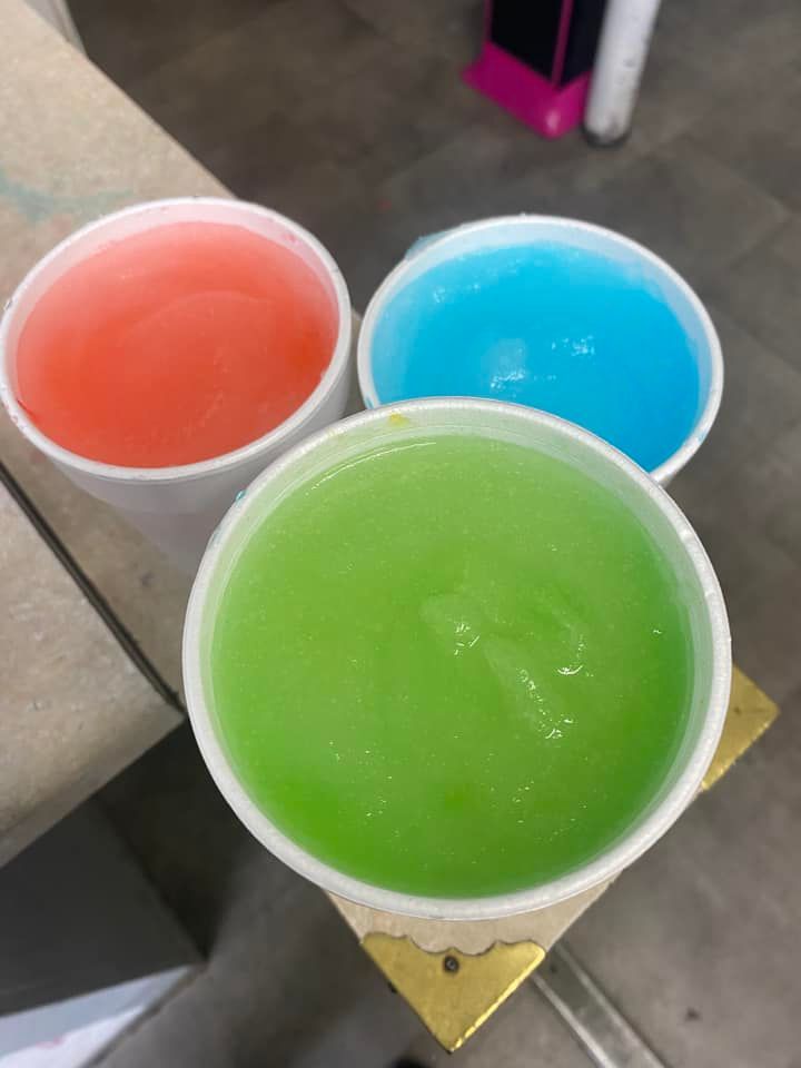 Three cups of different colored liquid are sitting on a table.