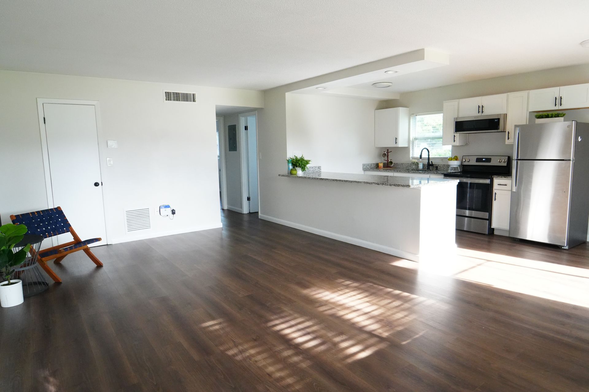 A living room with hardwood floors and a stainless steel refrigerator