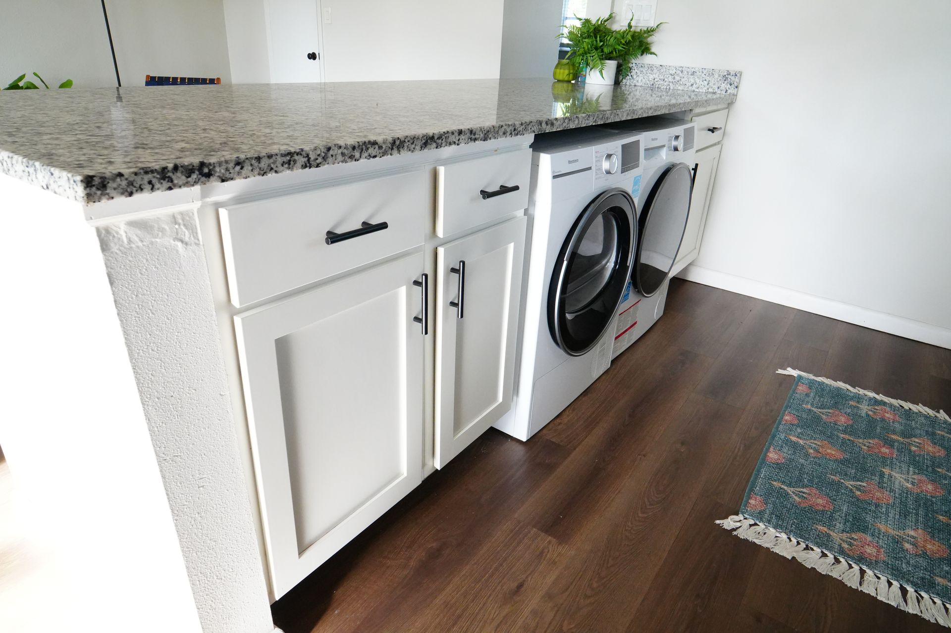 A laundry room with a washer and dryer and white cabinets