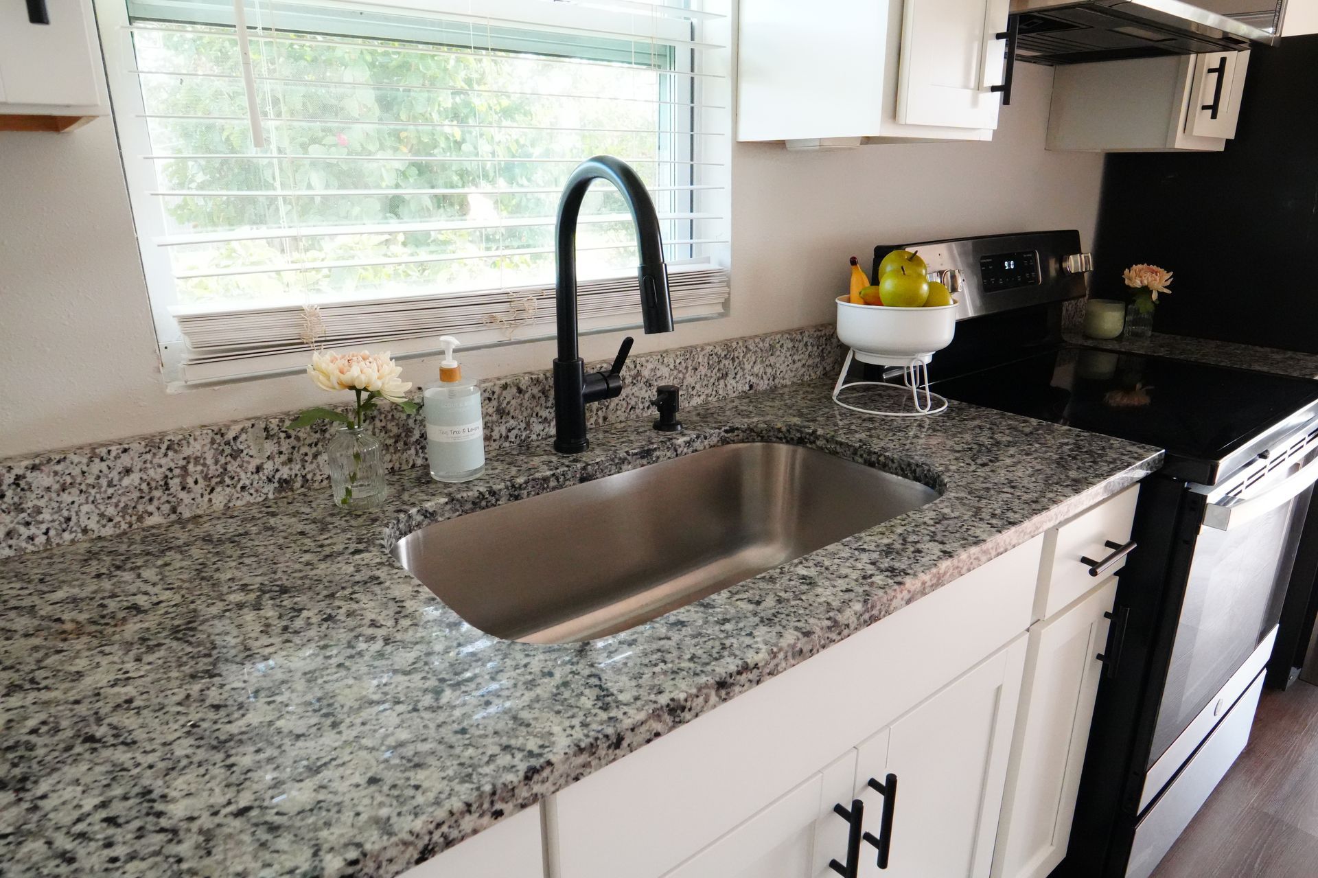 A kitchen with granite counter tops and a stainless steel sink.