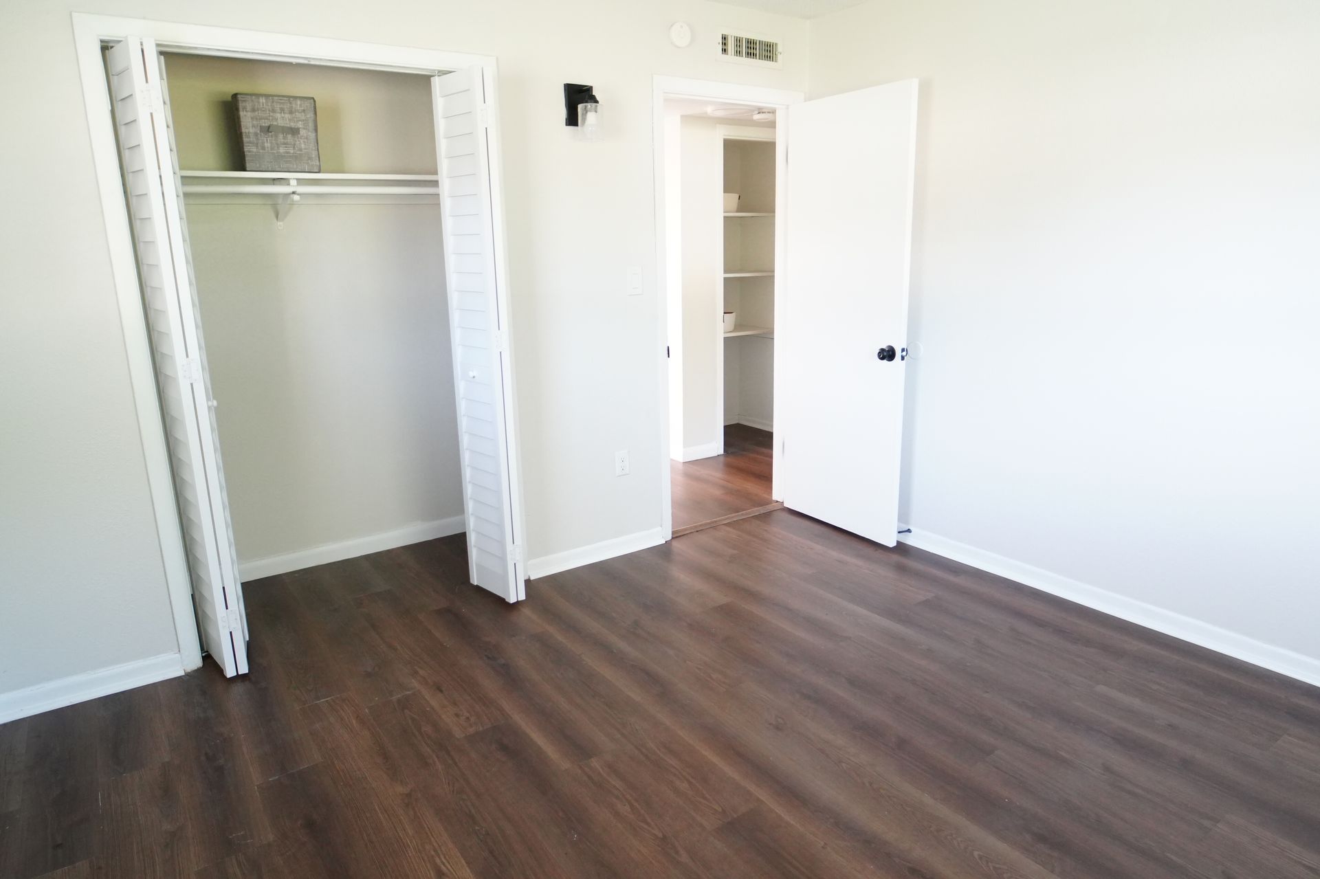 A bedroom with hardwood floors and a walk in closet.