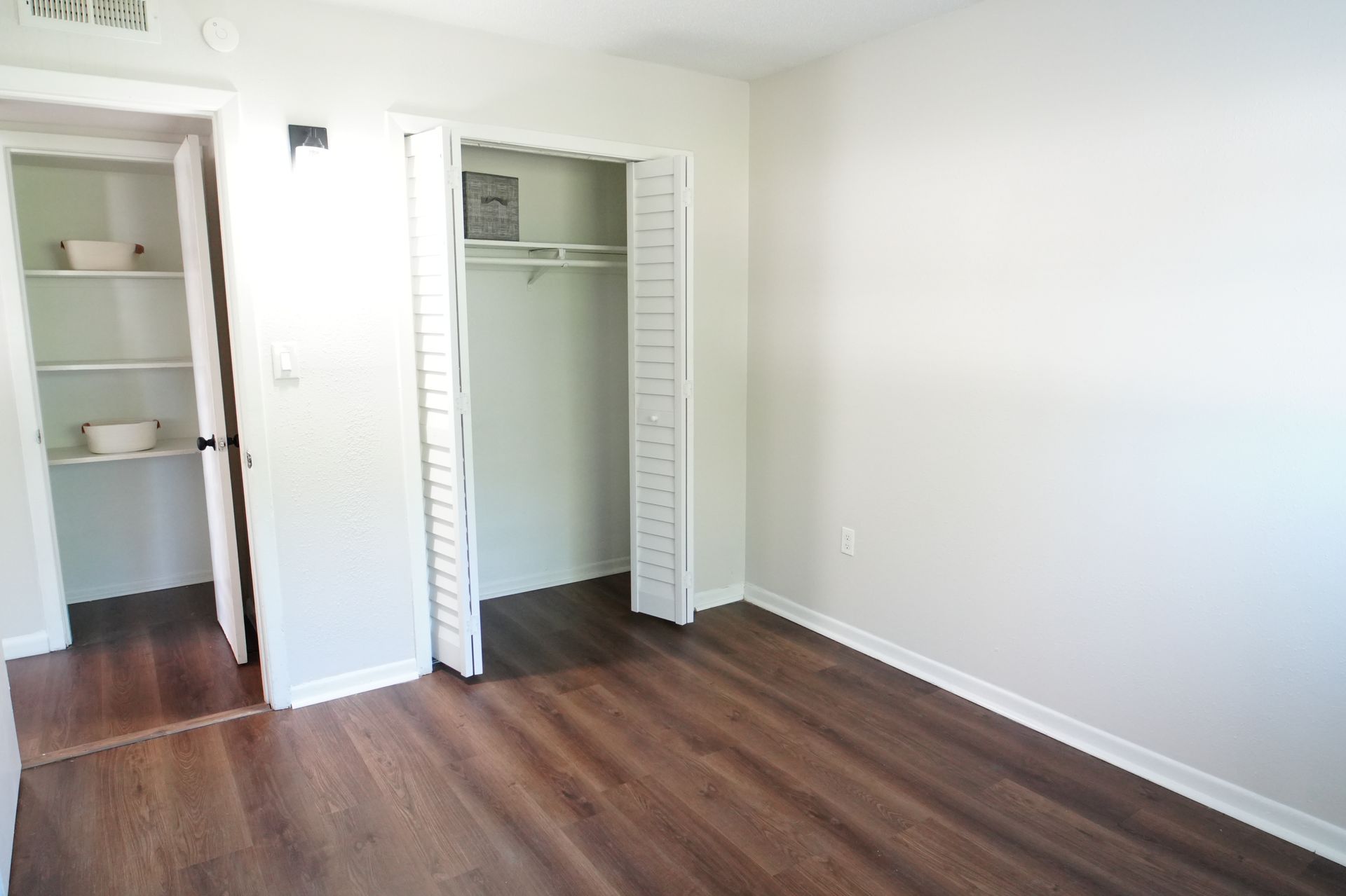 An empty bedroom with hardwood floors and a closet.
