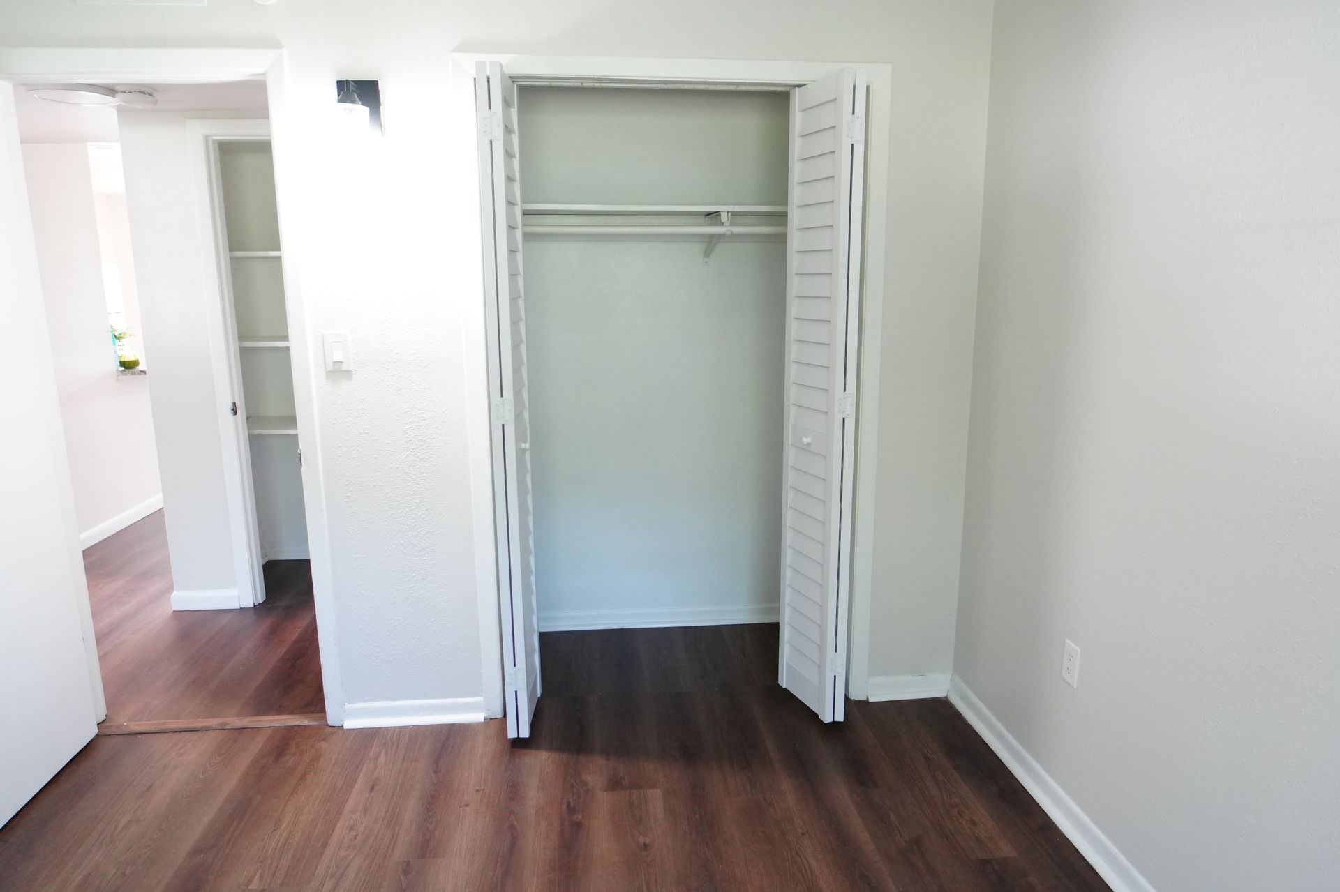 An empty bedroom with hardwood floors and a closet.