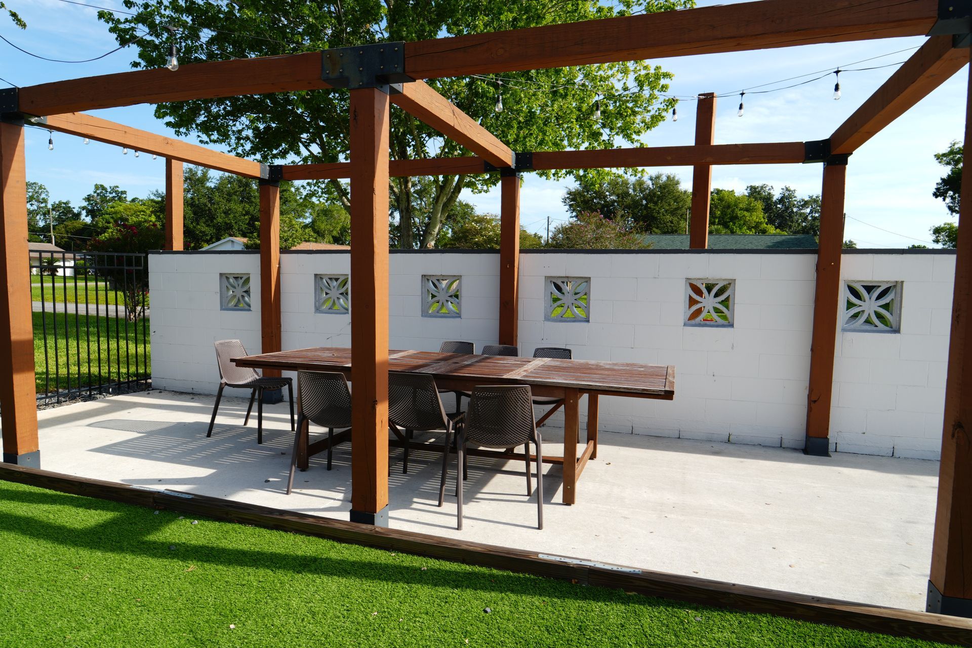 A wooden pergola with a table and chairs underneath it