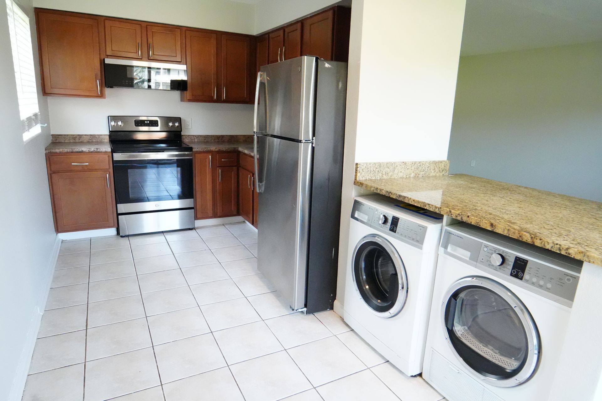 A kitchen with a refrigerator and a washer and dryer