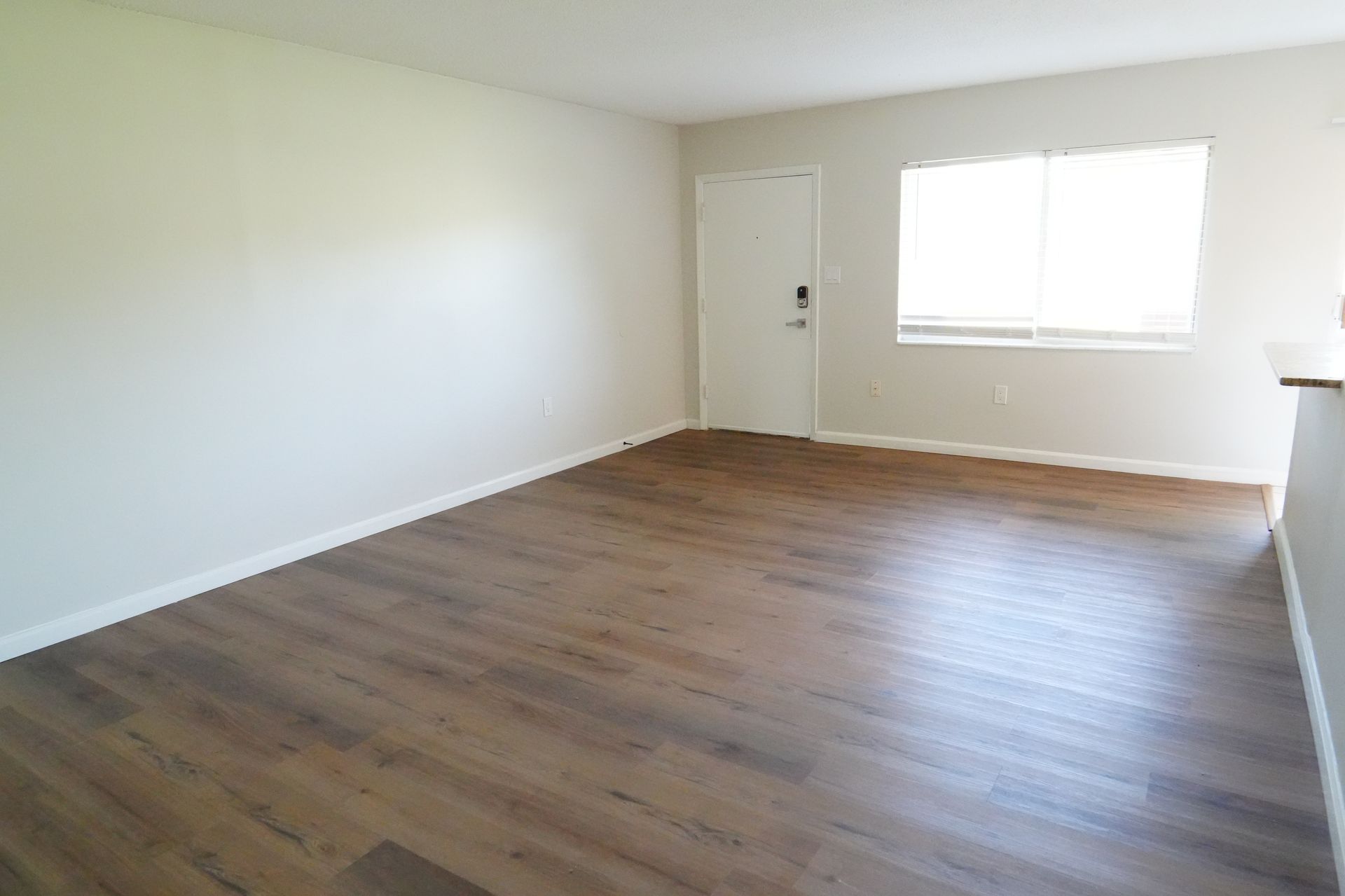 An empty living room with hardwood floors and a window.