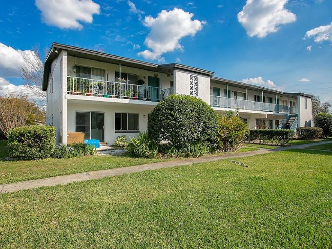A large white apartment building with a lush green lawn in front of it.