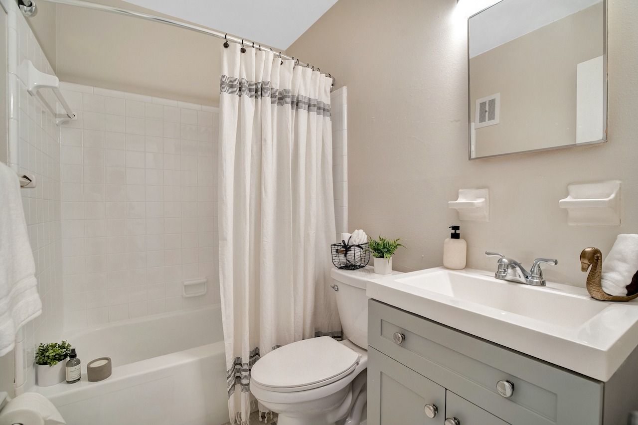 A bathroom with a toilet , sink , bathtub and shower curtain.