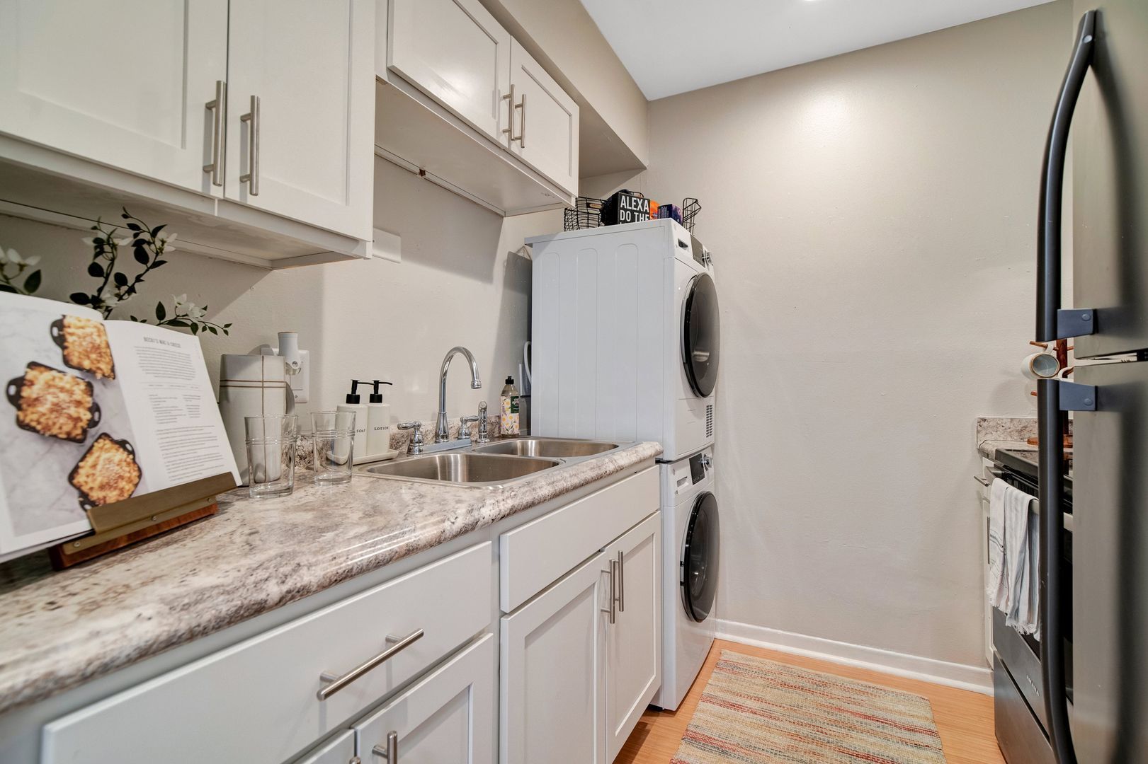 A kitchen with a sink , refrigerator , washer and dryer.