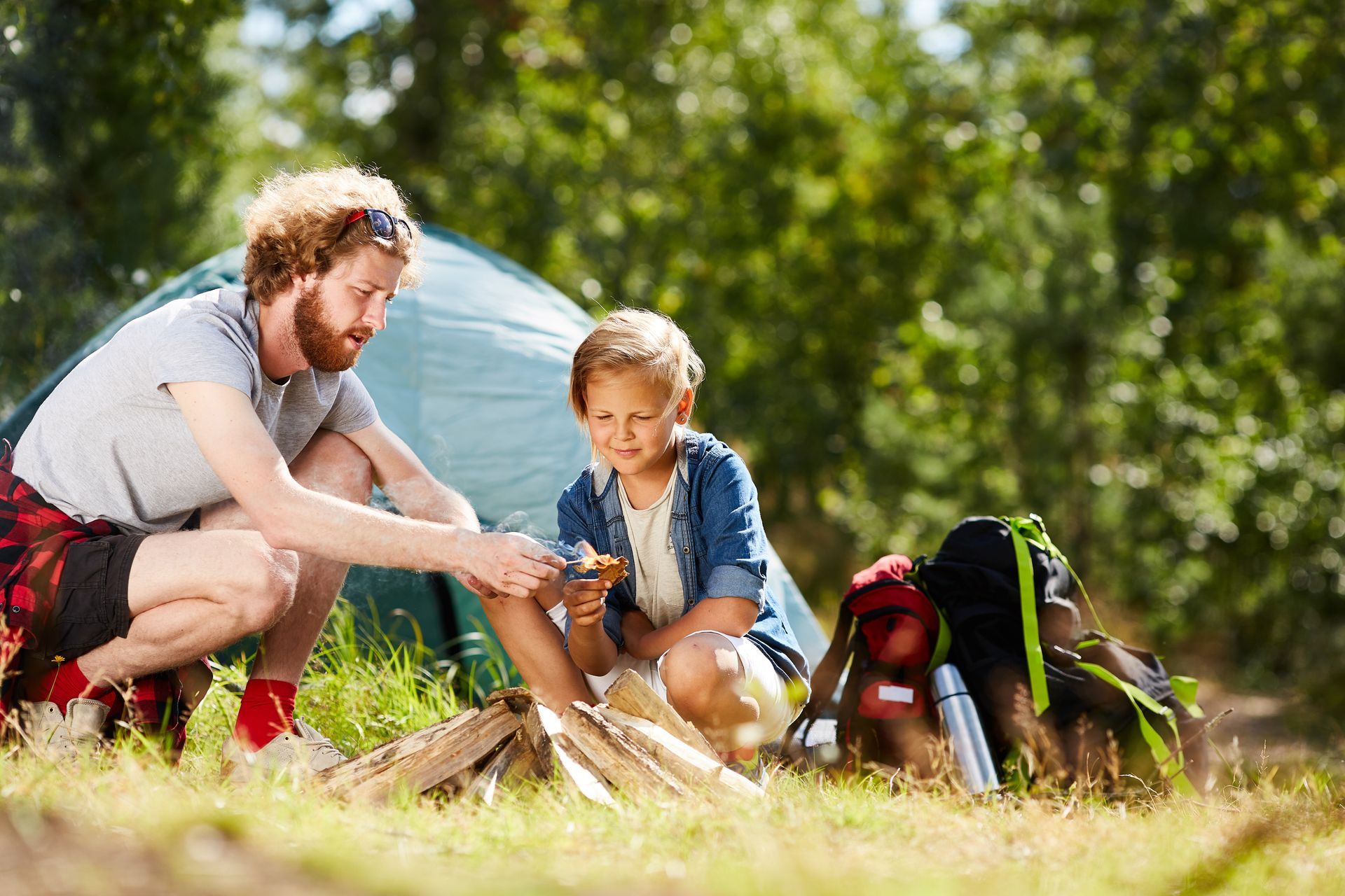 A group of people are setting up a tent in the woods.