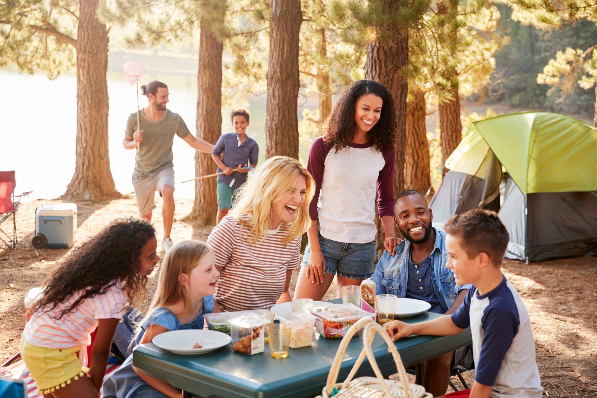 A group of people are sitting at a picnic table in the woods.