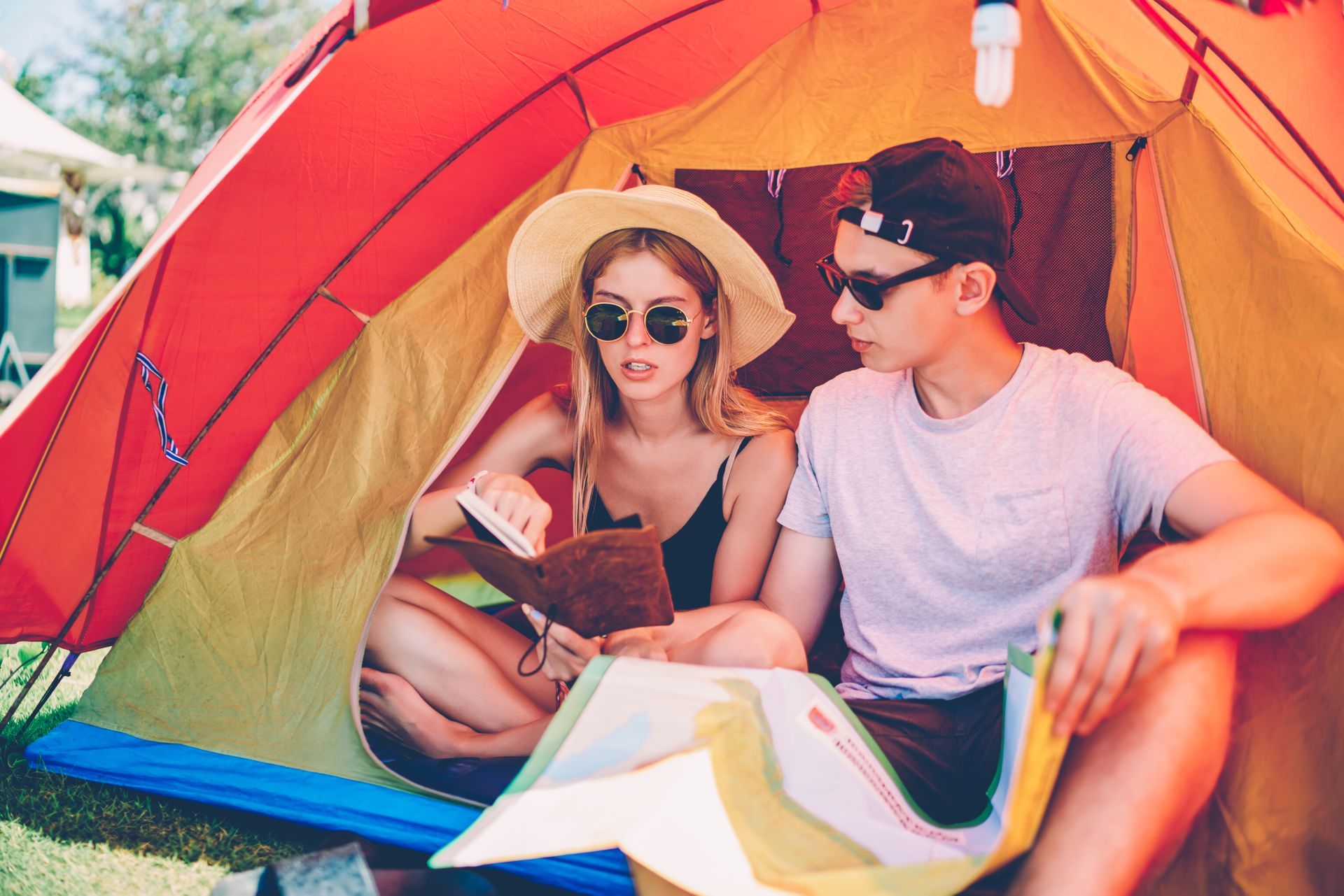 A man and a woman are sitting in a tent looking at a map.